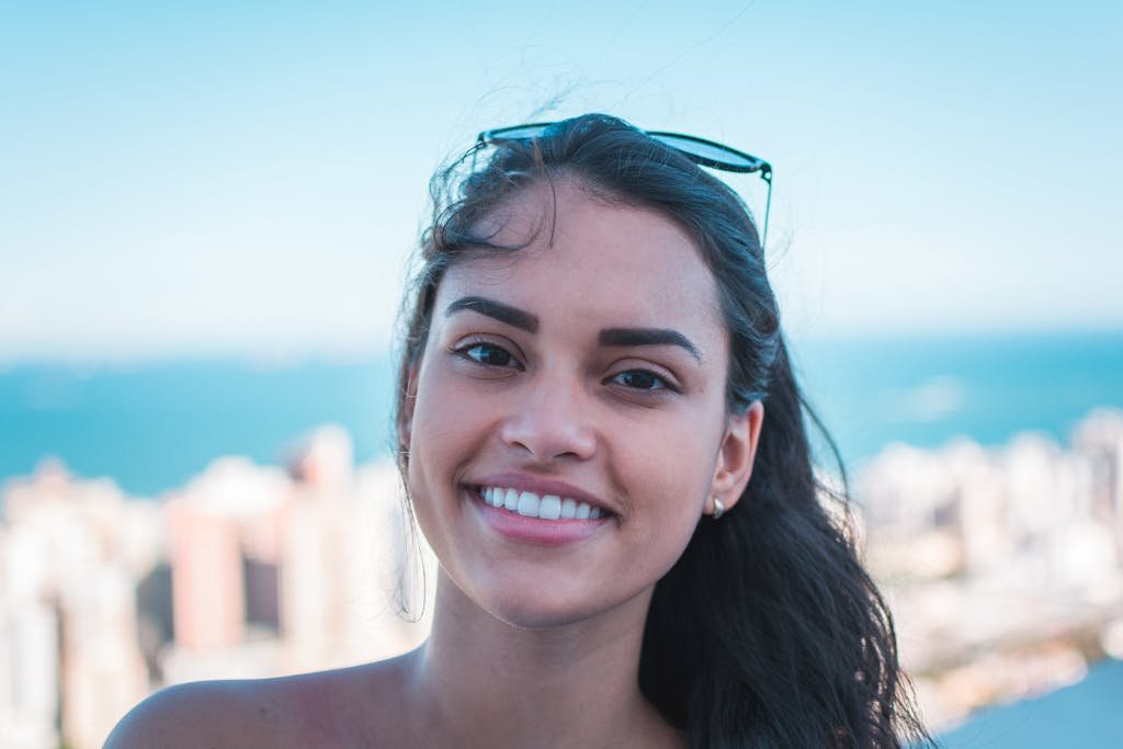 What Does Teeth Look Like Under Veneers: Why The Before And After Photos Are Misleading 9 Portrait of a happy woman smiling with sunglasses on head, city skyline view.