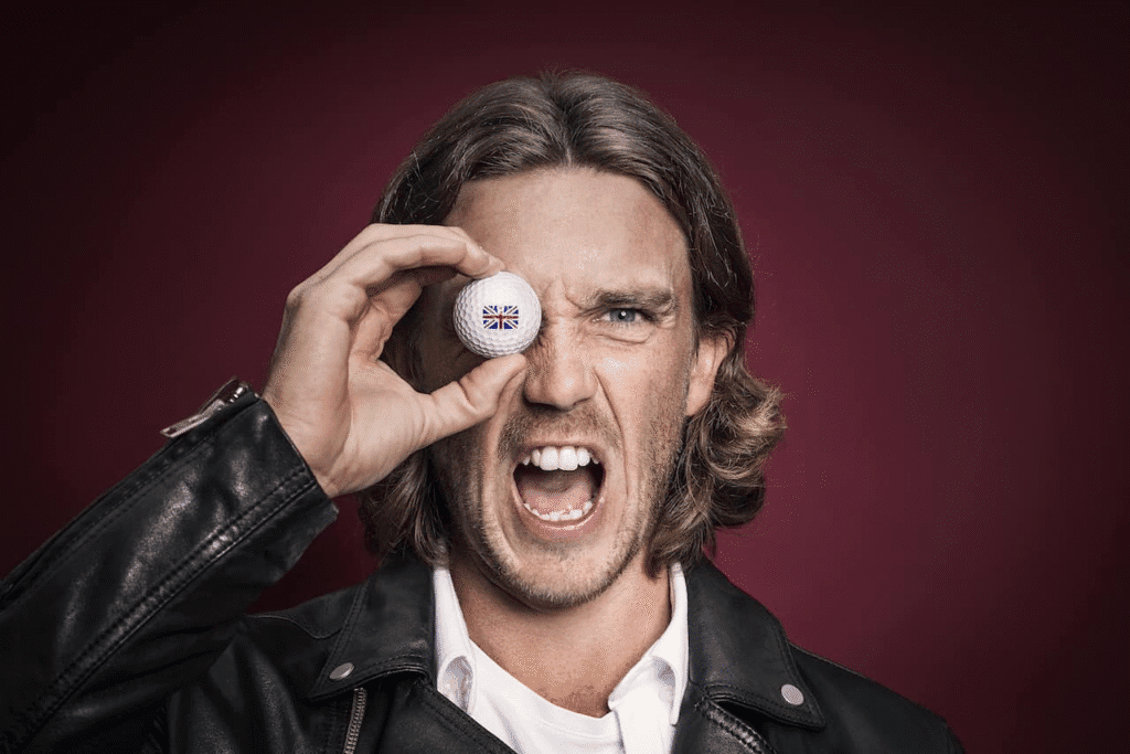 What Happened to Tommy Fleetwood’s Teeth? Porcelain Veneers and the Smile That Erased His Character 4 Tommy Fleetwood holding a golf ball with British flag over his eye while shouting, wearing a leather jacket and showing natural teeth