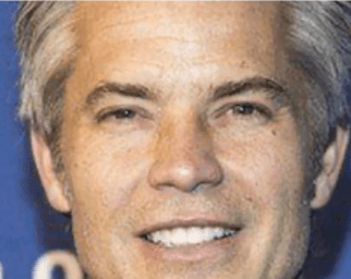 Timothy Olyphant’s Teeth Had Soul and Then Veneers Took It Away 3 Close-up of Timothy Olyphant smiling with bright, straight teeth, likely enhanced by porcelain veneers. His smile appears polished and symmetrical under event lighting.